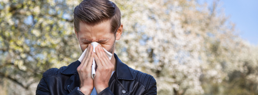 Man sneezing and suffering from seasonal allergies while outside