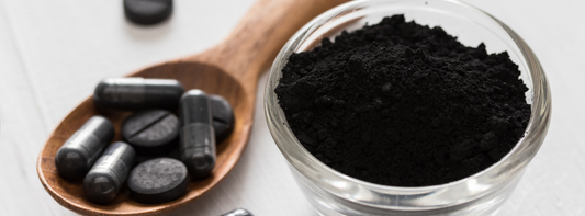 Spoon of activated charcoal powder in capsules and pills